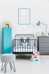 Child's bed with black metal frame in the middle of a pastel, scandi bedroom interior. Poster of a...