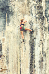 Fototapeta na wymiar Young woman climbs a rock with a risk to life