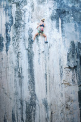 Fototapeta premium Young woman climbing a cliff without insurance. Toned