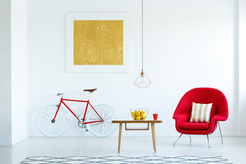 Real photo of a bright living room interior with a red armchair, wooden table with lemons in the...