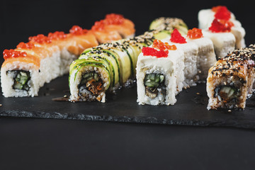 Set of different sushi rolls on black background