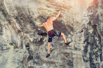 Obraz premium Young male mountaineer climbs on a rocky wall without insurance