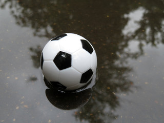 Soccer ball in the puddle. Football match in rainy weather
