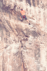 Rock climber on the cliff without insurance equipment. Toned