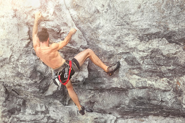 Fototapeta na wymiar Young male climber climbing a rock wall without insurance equipment. Toned