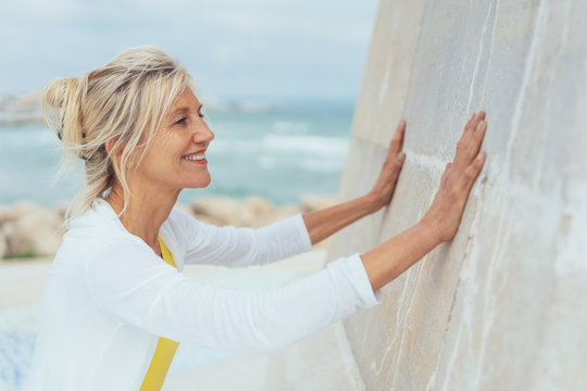 Happy blond woman leaning her hands on a wall