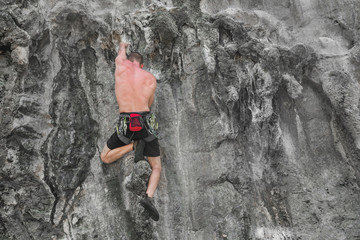 Young male climber climbing a rock wall without safety rope