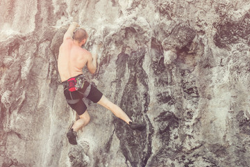 A man without safety equipment climbs the rock. Toned