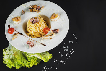 Tasty pasta with seafood on black background