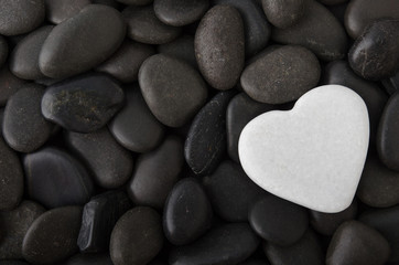 Fototapeta na wymiar Weißes Herz auf schwarzen Steinen
