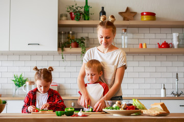 Photo of young mother with daughter and son cooking at table