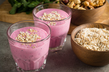 Glasses of berry smoothie with nuts, mint, blueberry, blackberry, raspberry, and yogurt on wooden table. Weight loss and diet concept. 