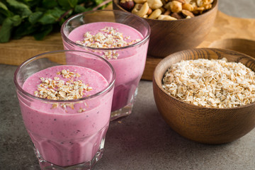 Glasses of berry smoothie with nuts, mint, blueberry, blackberry, raspberry, and yogurt on wooden table. Weight loss and diet concept. 