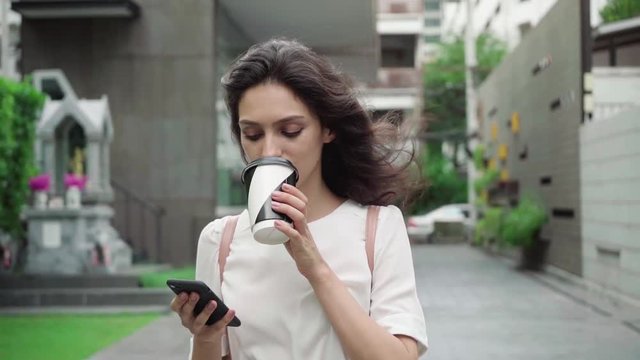 girl walking on city streets and drinking coffee to go in super slow motion
