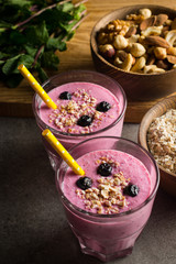 Glasses of berry smoothie with nuts, mint, blueberry, blackberry, raspberry, and yogurt on wooden table. Weight loss and diet concept. 