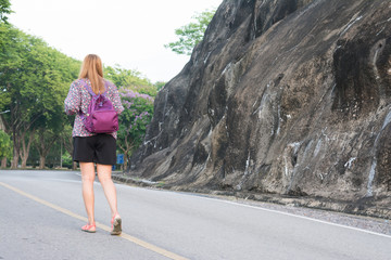 Back view of young woman with bag pack on the road, traveling concept.