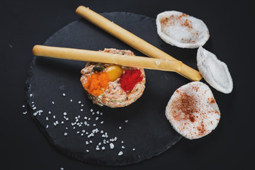 Tartar with caviar and bread sticks on black