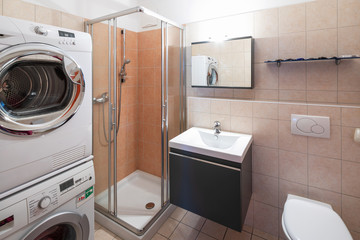 Modern bathroom with tile, shower, washing machine and dryer