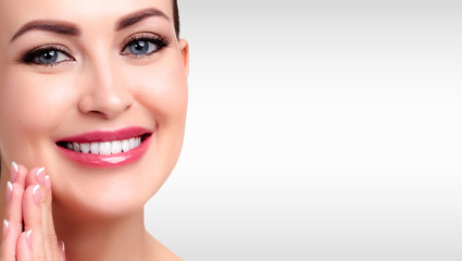 Fototapeta premium Pretty woman with smooth and soft skin smiling to you against a grey background with copyspace