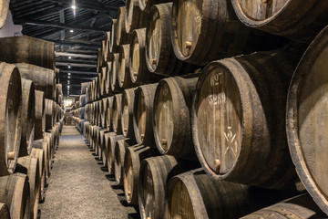 Row of wooden porto wine barrels in wine cellar Porto, Portugal.