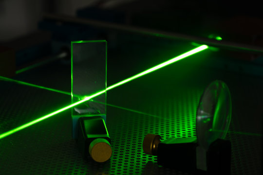Green laser on optical table in a quantum optics lab.