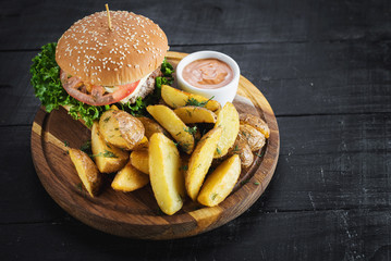 Tasty burger with fried potatoes on wooden board