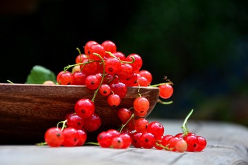 Rote Johannisbeeren in Holzschale auf rustikalem Holz  mit dunklem Natur Hintergrund