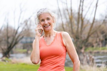 Senior woman in sport clothes receiving call on her mobile phone in a break
