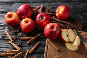 Fresh apples and cinnamon sticks on wooden background