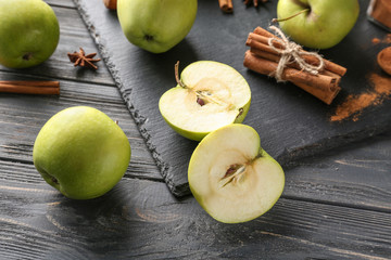 Fresh apples and cinnamon sticks on wooden background