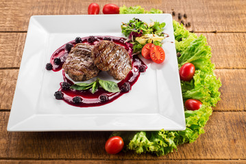 Grilled meat steak with raspberrie sauce on wooden background