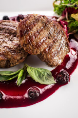Grilled meat steak with raspberrie sauce on wooden background