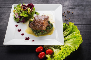 Fried piece of meat with herbs and spices on wooden background