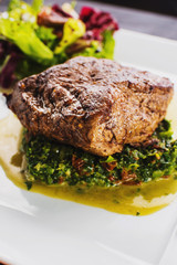 Fried piece of meat with herbs and spices on wooden background