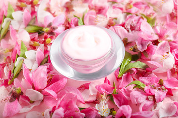 Fototapeta na wymiar Jar of cream with blooming flowers and petals on table