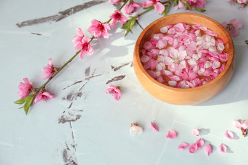 Wooden bowl with water and blooming flowers on table