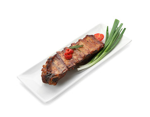Plate with delicious grilled ribs and green onion on white background