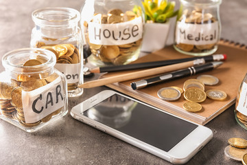 Coins for different needs in glass jars on table