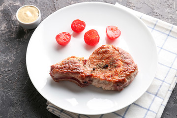 Plate with tasty grilled steak and tomatoes on table