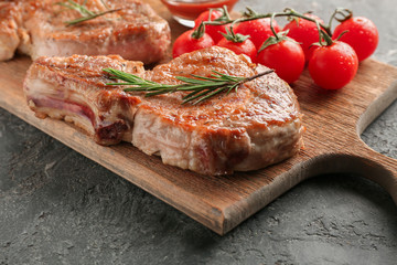 Tasty grilled steak and fresh tomatoes on wooden board, closeup
