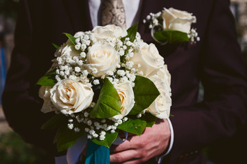 delicate bouquet of white roses in the hands of the groom