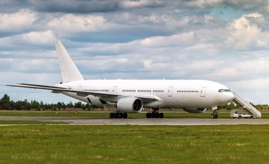 Wide body passenger airplane with boarding stairs at the airport apron
