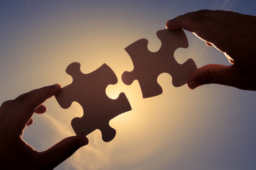Hand putting puzzle piece together. 
