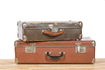 Old vintage suitcases on light wooden table isolated on a white background. Travel concept.