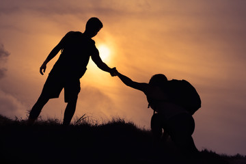 Challenge yourself, teamwork and people helping each other concept. 
Hikers climbing up mountain. 