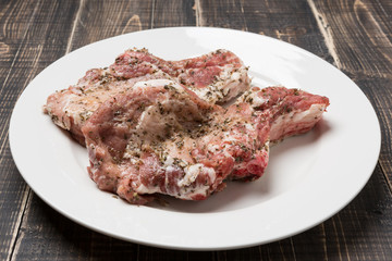 two pieces of steak with spices, raw meat in a white plate on a wooden table, rustic style