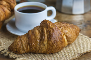 French breakfast with cup of coffee and hot croissants in rustic style