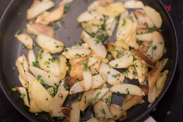Fried potatoes with green onion on a metal pan