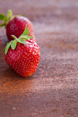 Strawberries ripe on a rustic rust background. Copy space. Healthy lifestyle concept. Vertical image