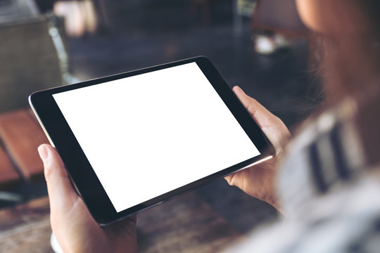 Mockup image of a woman holding and using black tablet pc with white blank screen